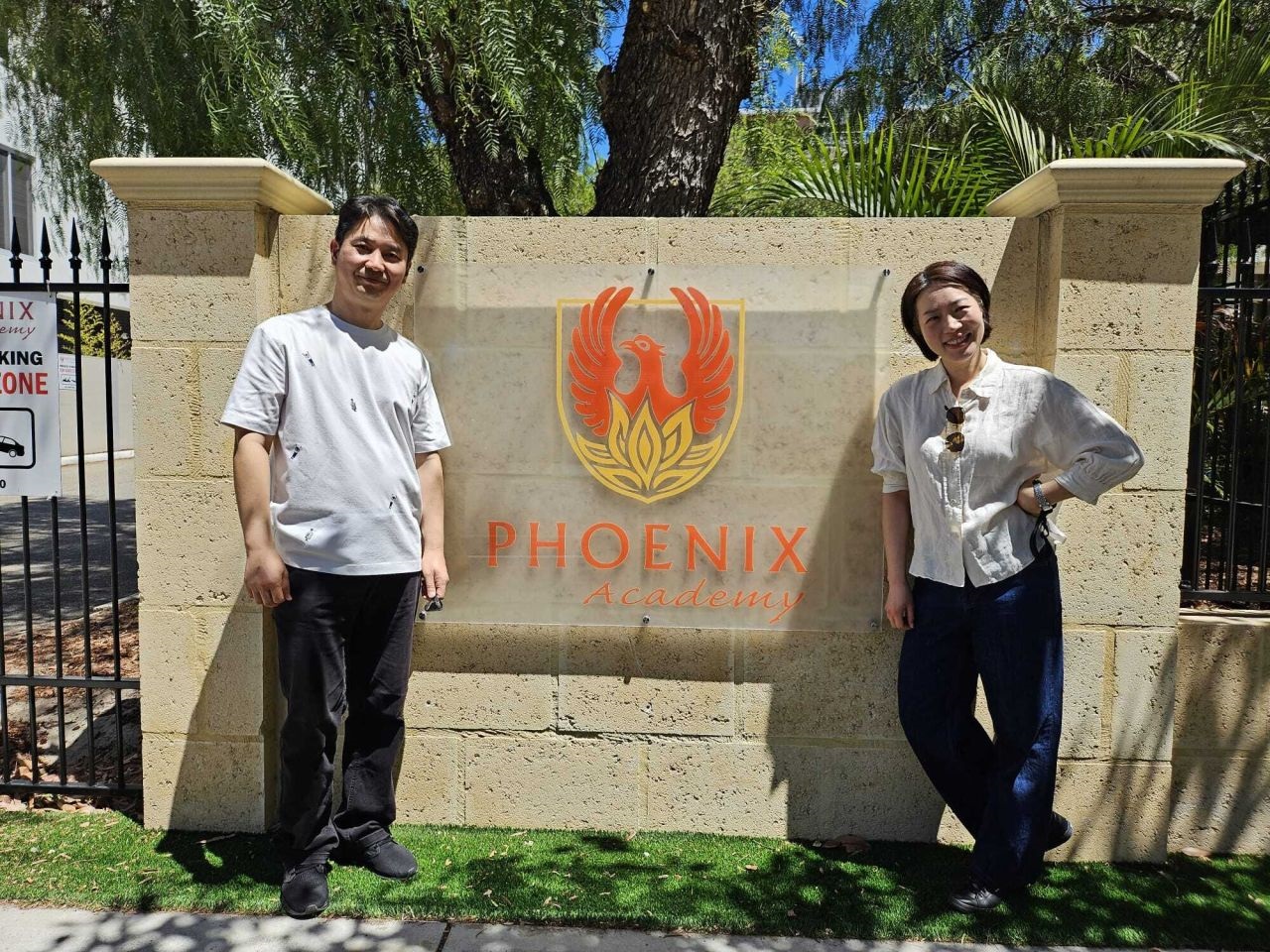 Two South Korean students stand out the front of Phoenix Academy sign